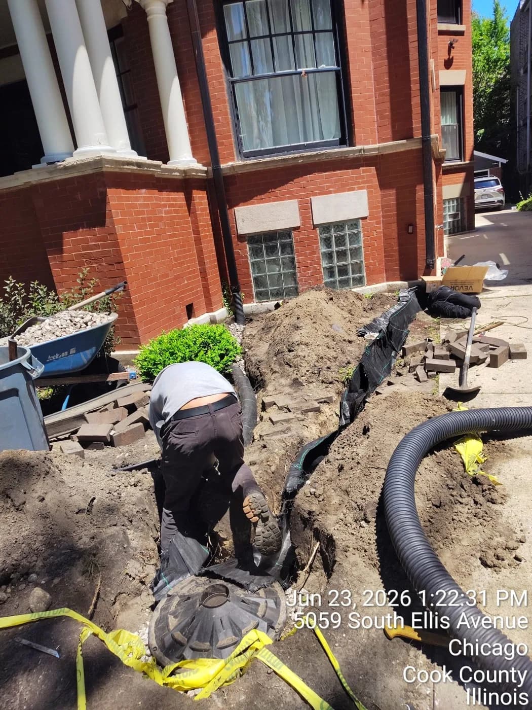 Downspout drain and basin dug in tight along a greystone foundation